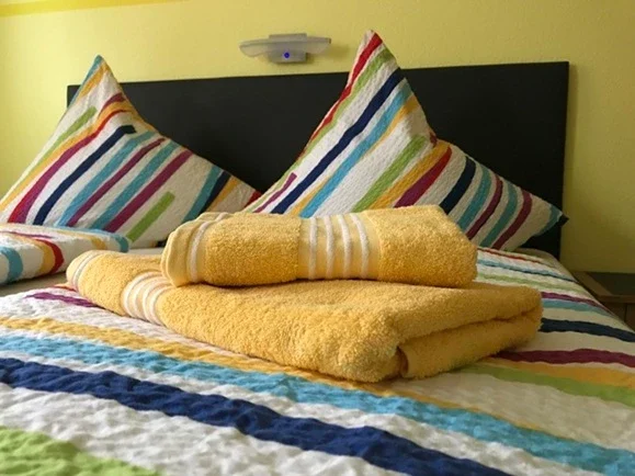 Frisch bezogenes Doppelbett mit Handtüchern in der Pension - Gästehaus Legden für Urlauber, Monteure und Radfahrer.