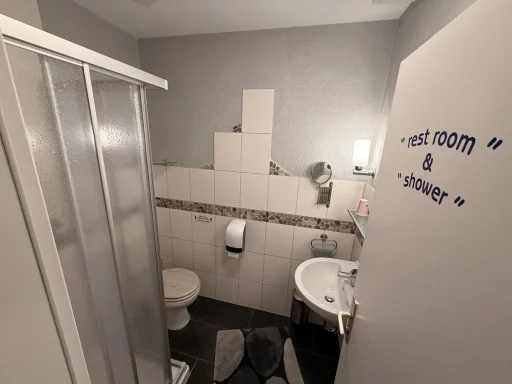 Sauberes Gäste-Badezimmer im Gästehaus Legden mit Dusche, WC, hellem Waschbecken und moderner Wandgestaltung.