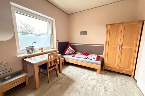 Helles Gästezimmer der Pension & Gästehaus Legden mit Einzelbett, Schreibtisch und Kleiderschrank – Unterkunft nahe Münster