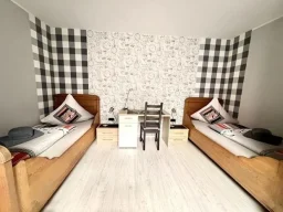 legden-pension-zweibettzimmer-wohnen Zimmer mit Bett, Fernseher und Schreibtisch für Monteure in der Pension Legden.