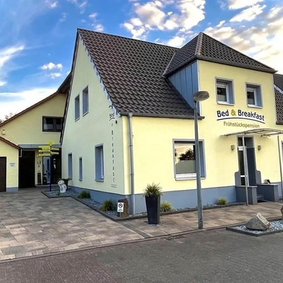 Moderne Außenansicht der Pension Gödde in Legden im Münsterland mit Parkplatz und Fahrradgarage.