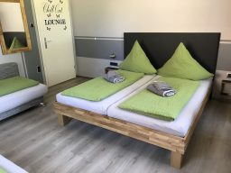 Zwei Einzelbetten mit grünen Kissen und grauen Handtüchern im Zimmer der Pension Bed and Breakfast.