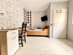 legden-pension-zweibettzimmer-wohnen Schönes Zimmer in der Pension mit einem Einzelbett, Schreibtisch und TV an der Wand.