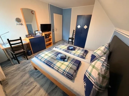 Gemütliches Doppelzimmer mit Fernseher und Schrank in der Pension - Gästehaus Legden.