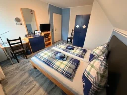 Hell eingerichtetes Doppelzimmer in Legden mit Kleiderschrank, Schreibtisch und Fernseher für Gäste.