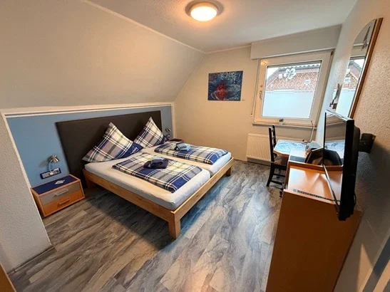 Gemütliches Doppelzimmer in Legden mit großem Bett, Fernseher und Schreibtisch für Urlauber und Gäste.