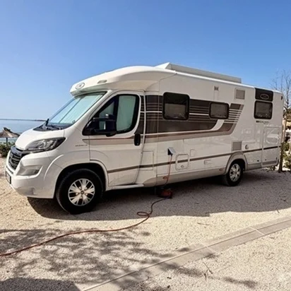 Weißes LMC Wohnmobil auf einem Campingplatz am Meer unter blauem Himmel als Inspiration für das Gästehaus Legden im Münsterland.