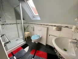 Helles Badezimmer mit Dusche, WC, Föhn und großem Dachfenster in der Pension - Gästehaus Legden.